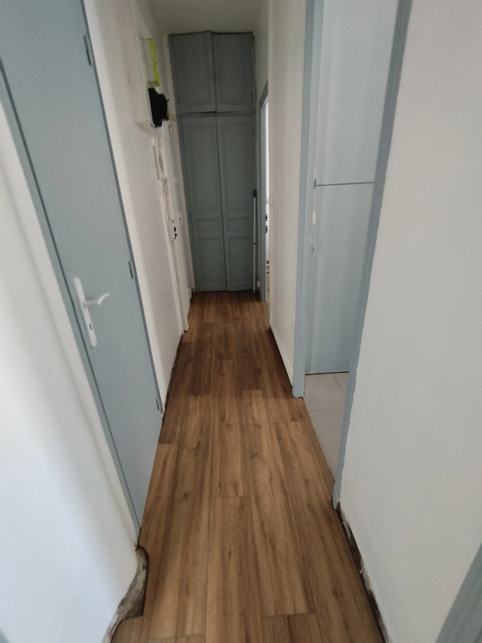 Continuité du sol stratifié effet bois dans le couloir d’un appartement à Marseille 13003