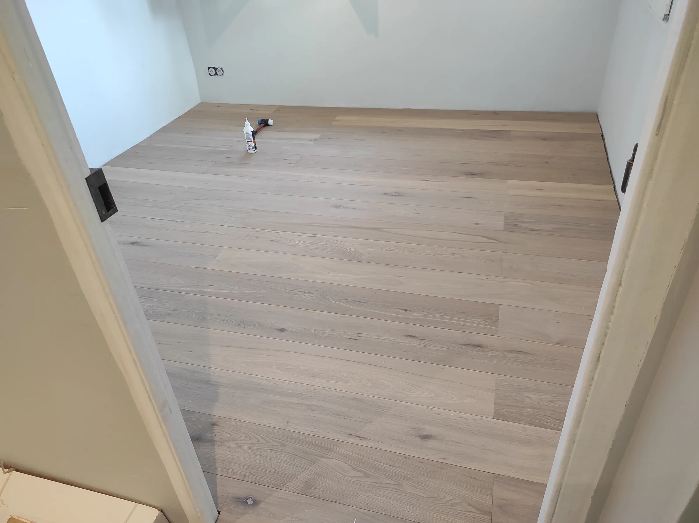Ajustements du parquet bois clair pendant la pose dans une pièce à Nice